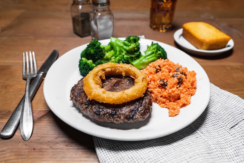 beef chopped steak with an onion ring, carrot raisin salad, broccoli, and cornbread