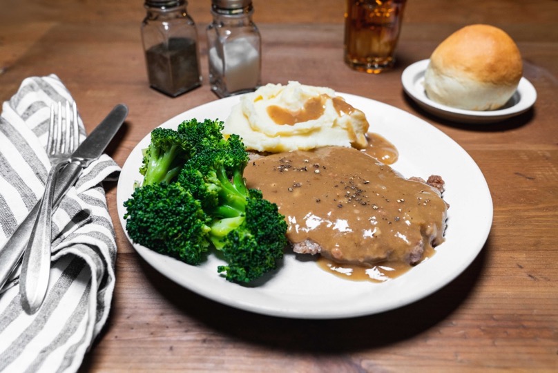 beef country steak with mashed potatoes and gravy, broccoli, and a roll