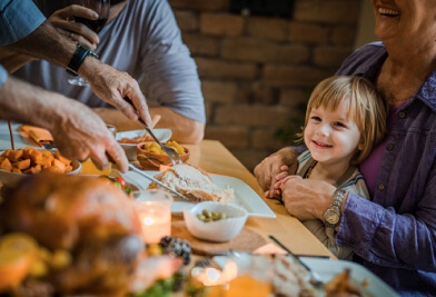 Little girl smiling at the dinner table in grandmas lap