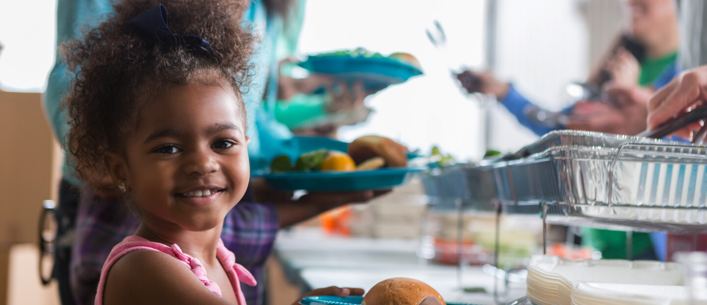 little girl smiling while getting catered food