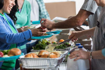 People serving themselves food from a catering table