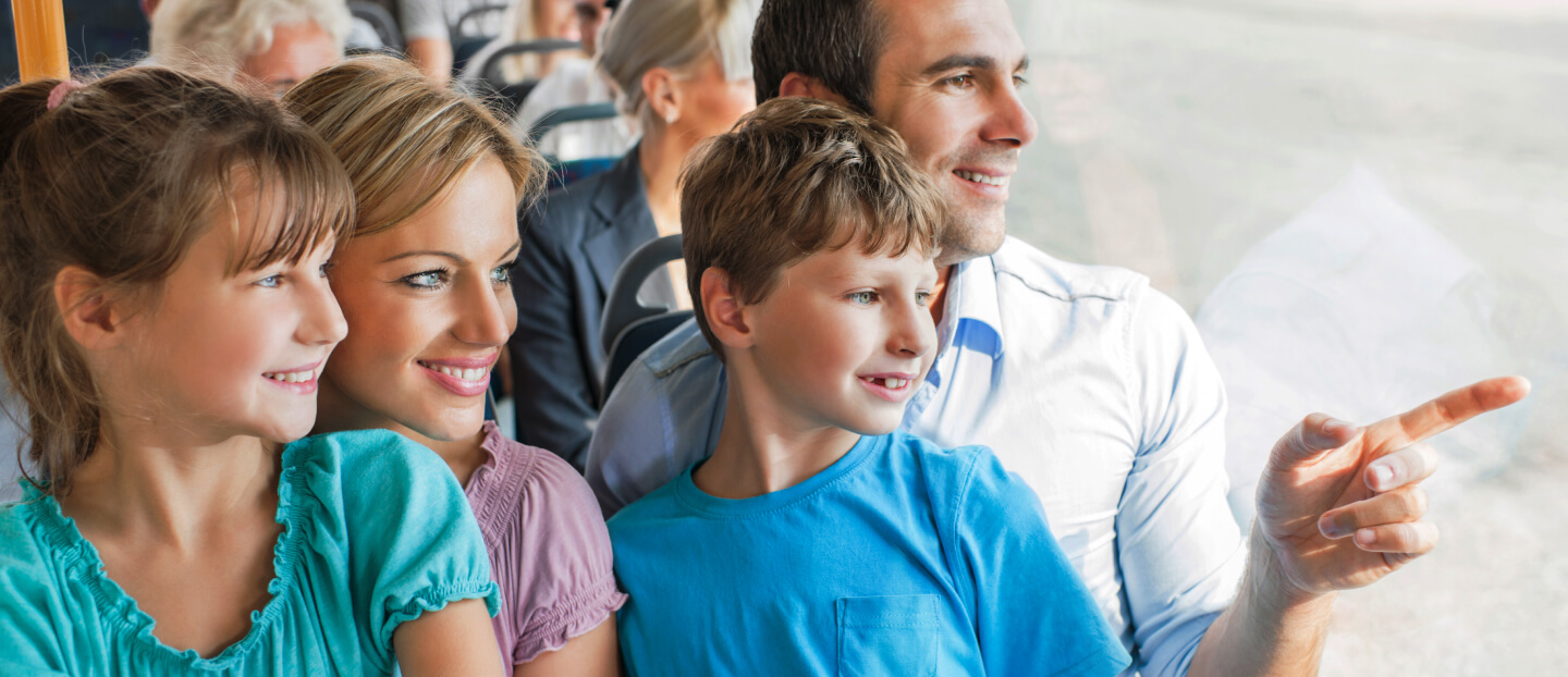 Parents on bus pointing out a window for their children