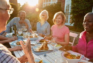 Happy seniors sitting at table outside eating dinner